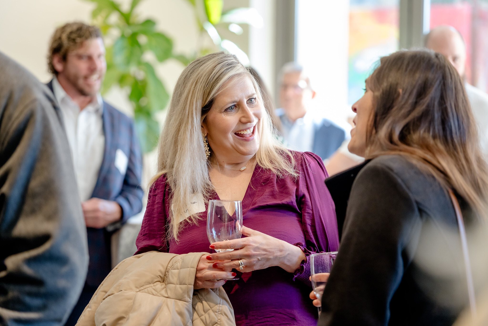 Two women in conversation at a reception, glasses in hand